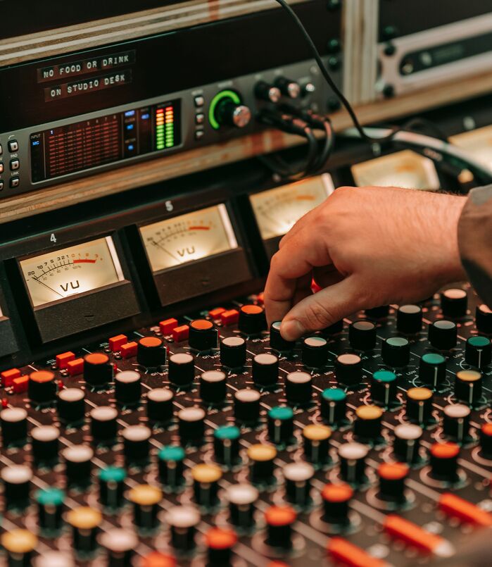 Hand adjusting gain on a studio mixing console